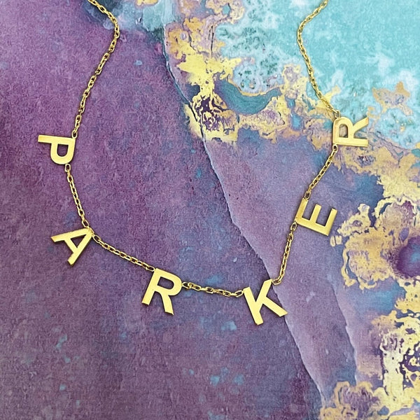 hanging name necklace parker on purple marble background
