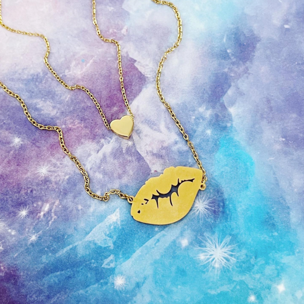 This is an image of our mini gold necklace layered with our gold lip kiss necklace on a purple and blue background