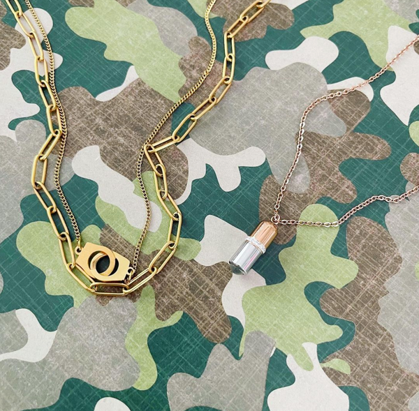this is an image of our gold layered handcuff necklace with our chillpill necklace on a camo background