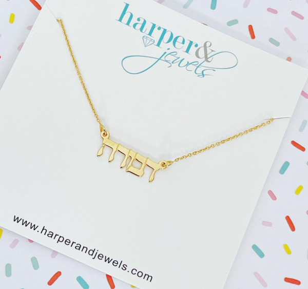 This is an image of our gold hebrew nameplate necklace on a sprinkle background