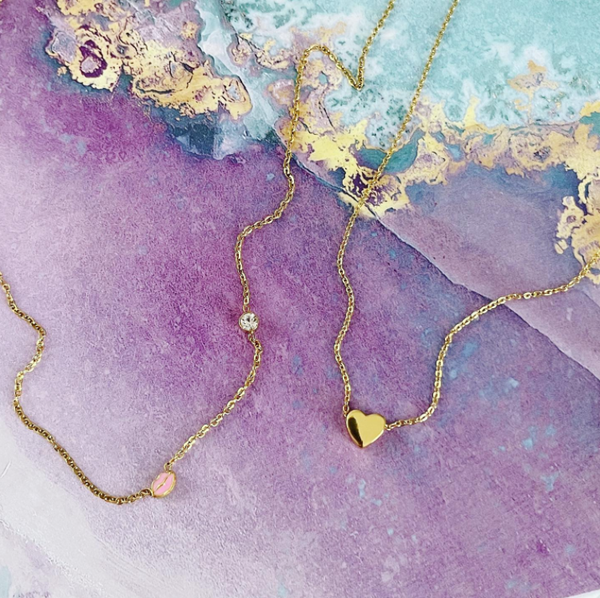 This is an image of our Lip & stone necklace with our Mini heart necklace on a purple and blue marble background