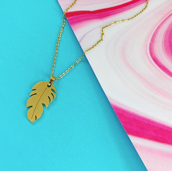 This is an image of our gold leaf pendant necklace on a blue and pink background