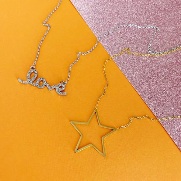 This is an image of our cz love necklace and gold stars hollow necklace on an orange and pink background
