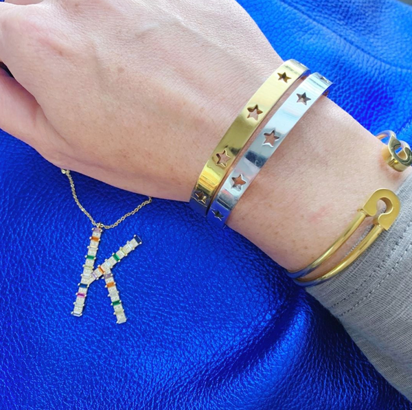 This is an image of our gold and silver star struck bangles on a blue background with a rainbow initial necklace