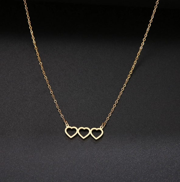 This is an image of our gold triple heart necklace on a black background