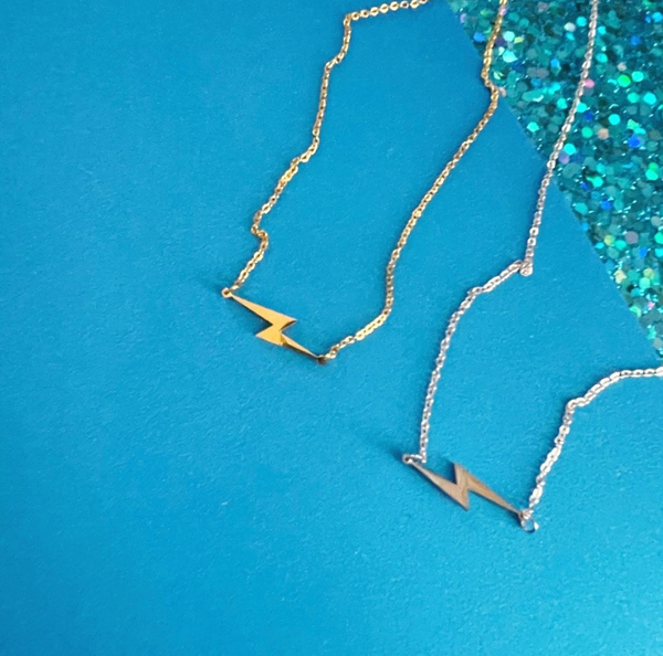 silver and gold lightning bolt necklaces on blue paper