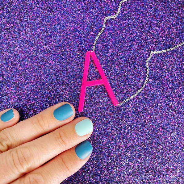 Pink color pop A necklace on purple glitter background with blue manicure
