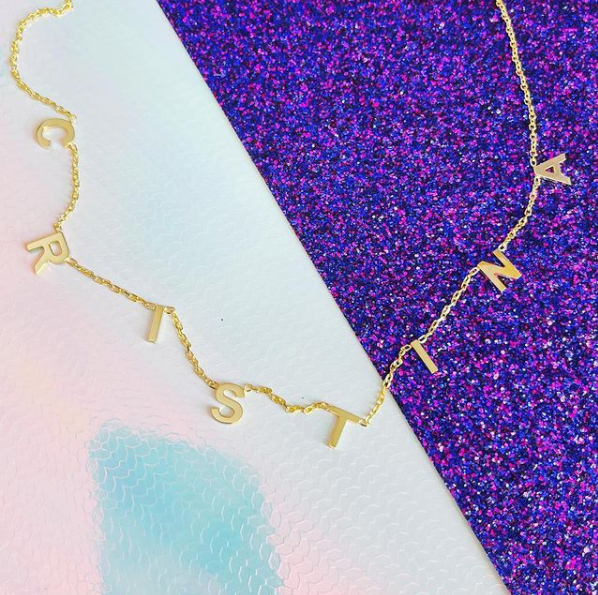 Dainty hanging name necklace CRISTINA on purple glitter background