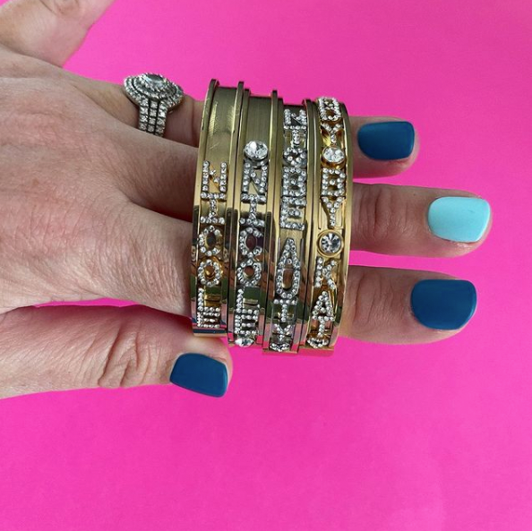 personalized sliding charm bangle bracelets on pink background with blue manicure