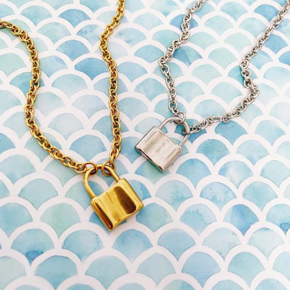 gold and silver lock pendant necklaces on mermaid scale background