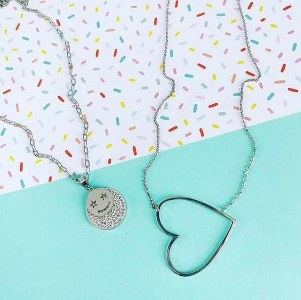 smiley star face necklace with open heart necklace on sprinkle background