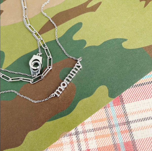 This is an image of our layered silver handcuff necklace with our silver mommy necklace on a camo background