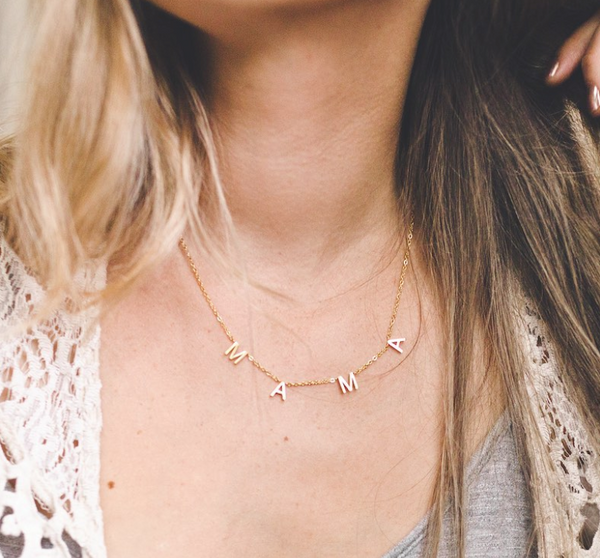 This is an image of our hanging letter MAMA necklace in gold on our model.