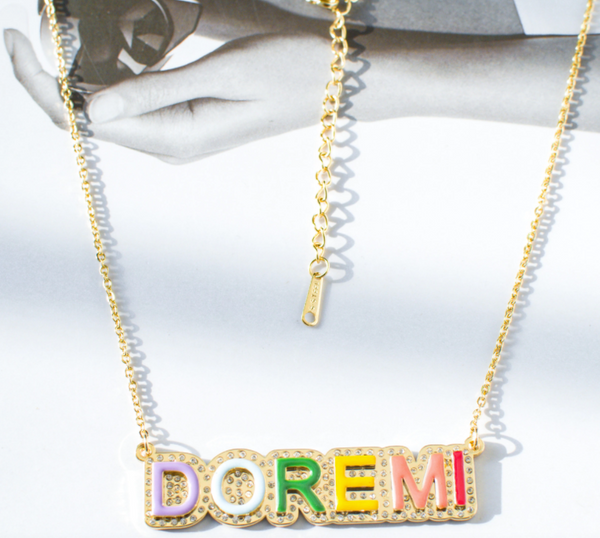This is an image of our gold iced rainbow nameplate necklace on a white background