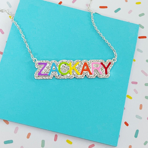This is an image of our iced nameplate necklace reading "Zachary" on a blue background