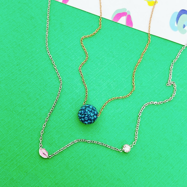 Thi is an image of our CZ disc necklace with our lip & stone necklace on a green background