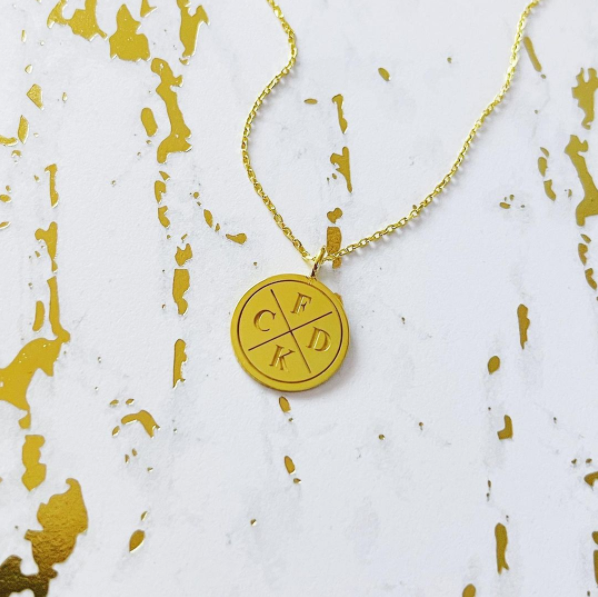 This is an image of our gold family coin disc necklace on a white and gold marble background