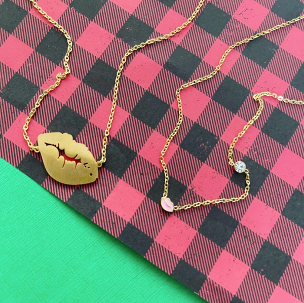 This is an image of our gold lip kiss necklace with our gold lip & stone necklace on a red and black buffalo check background