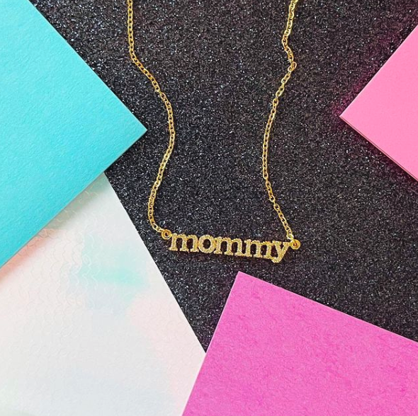 This is an image of our gold mommy cz necklace on a pink and blue glitter background