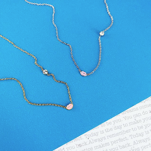 This is an image of our cz pink lip and stone dainty necklace on a white and blue background