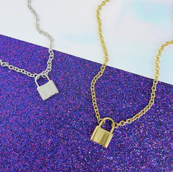 This is a picture of our silver and gold lock necklaces on purple glitter background