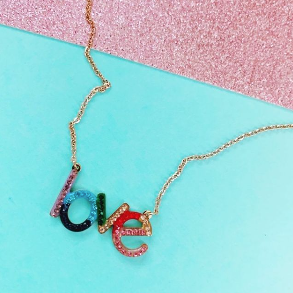 This is a photo of our rainbow love necklace on a teal and pink background