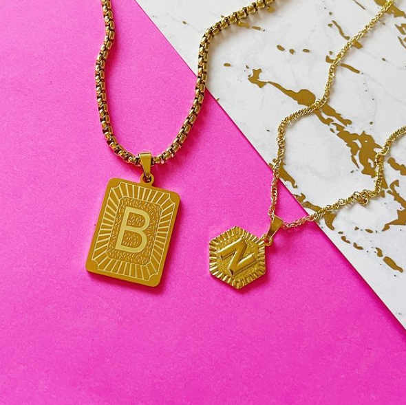 This is an image of our rectangle and hexagon medallion necklaces on a pink and marble background