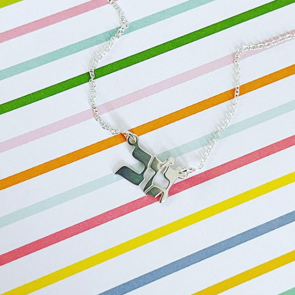 Silver hebrew nameplate necklace on a striped background