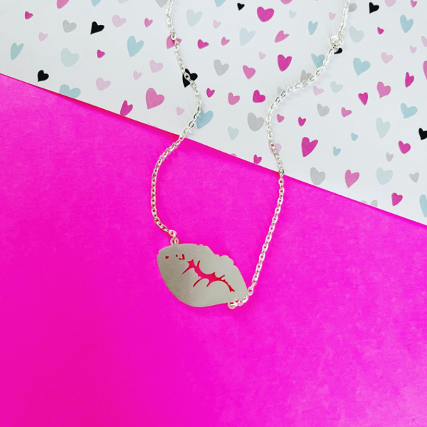 This is an image of our lip kiss necklace on a pink and heart background