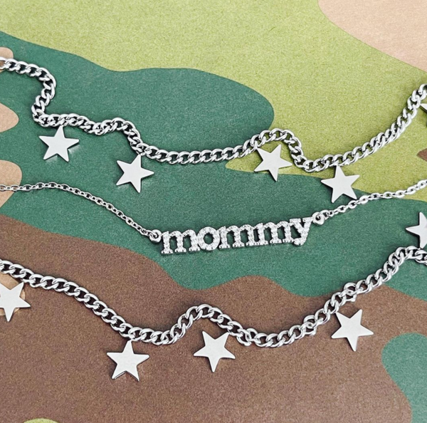 This is an image of our hanging star charm bracelets with our cz mommy necklaces on a camo background