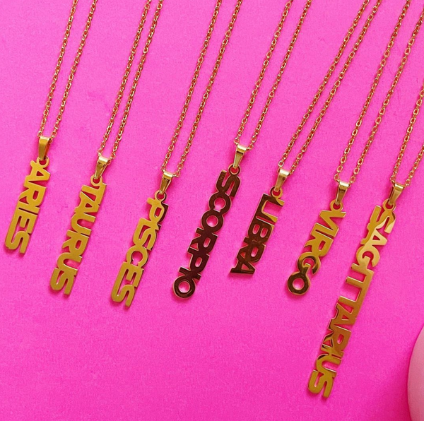 This is an image of our zodiac nameplate necklace on a pink background